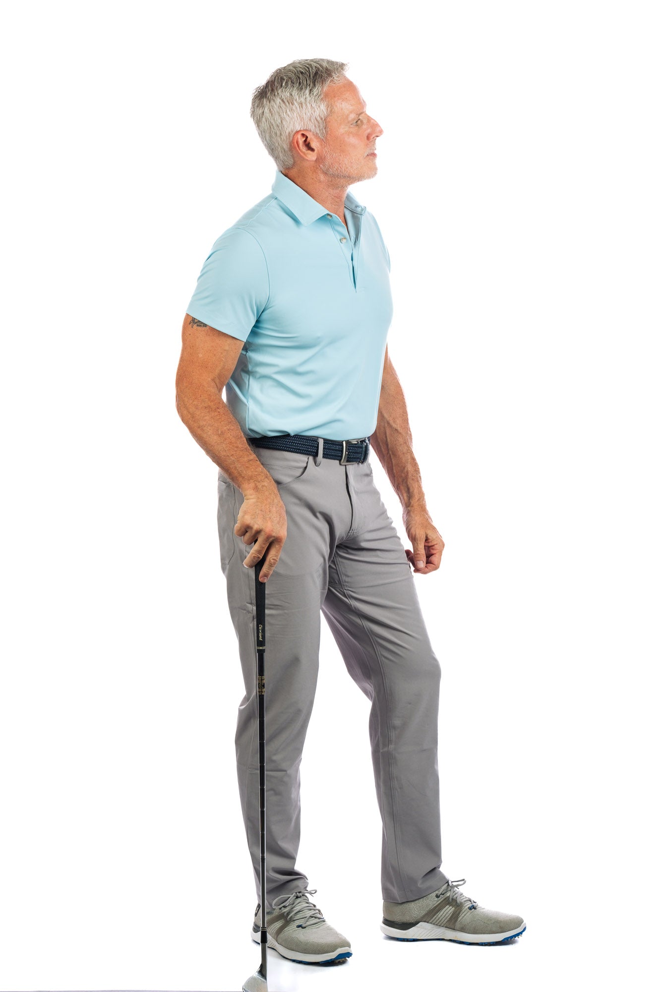 Side profile of model wearing light blue golf polo and concrete golf pants looking to the right. 