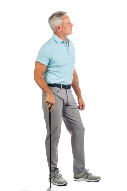 Side profile of model wearing light blue golf polo and concrete golf pants looking to the right. 