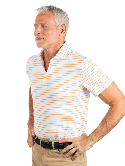Waist up photo of model wearing the Orange striped golf polo on a white background looking to the left. 