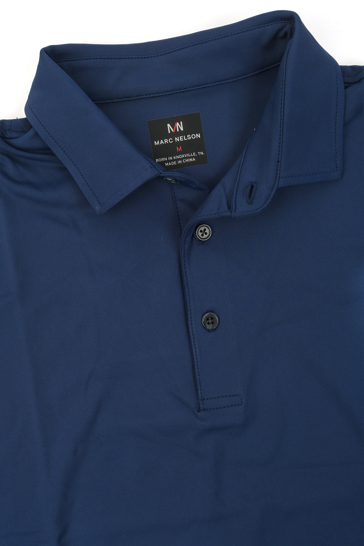 Close up photo of navy golf polo showing the details including the collar and button. 
