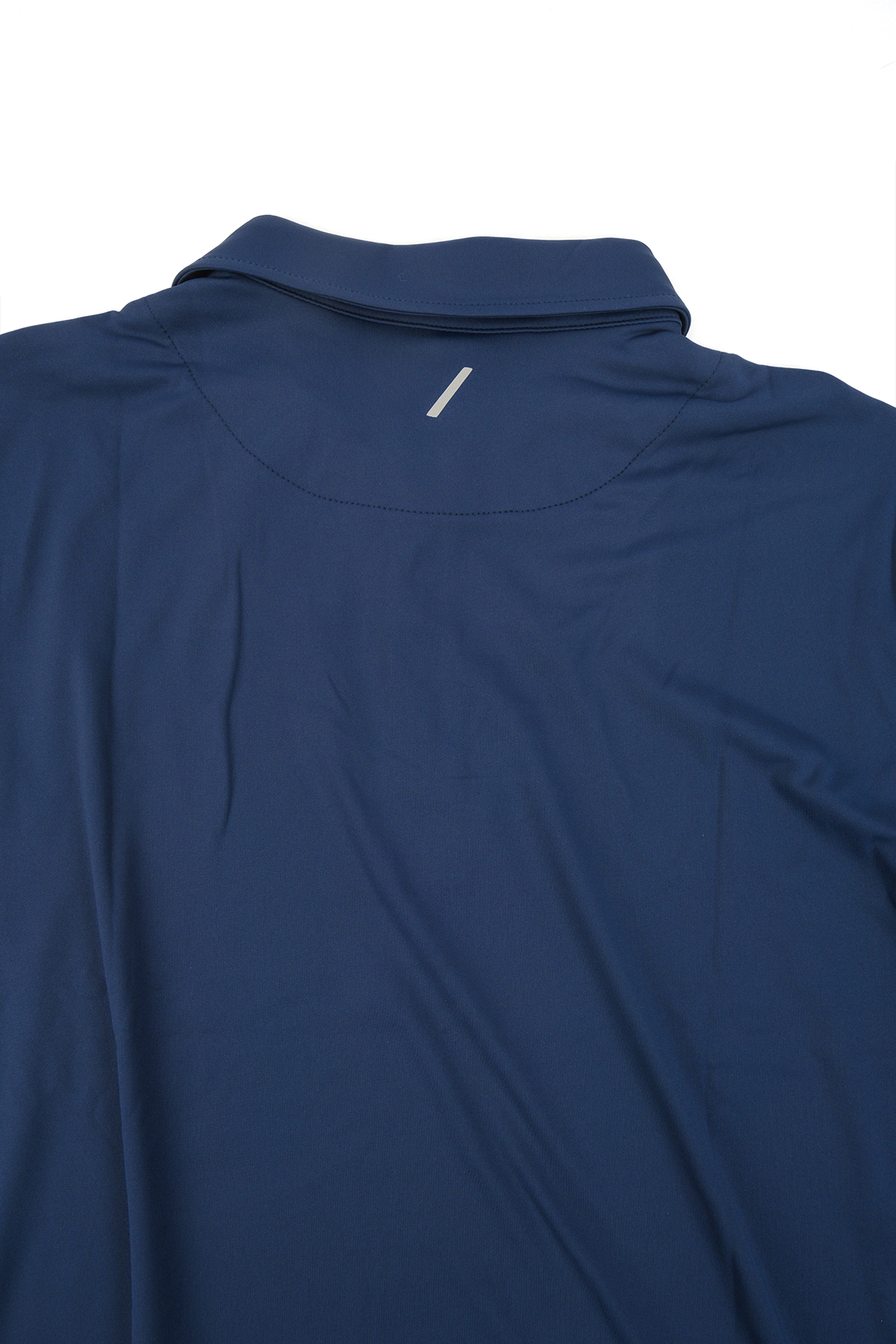 Close up photo showing the backside of the navy golf polo on a white background.