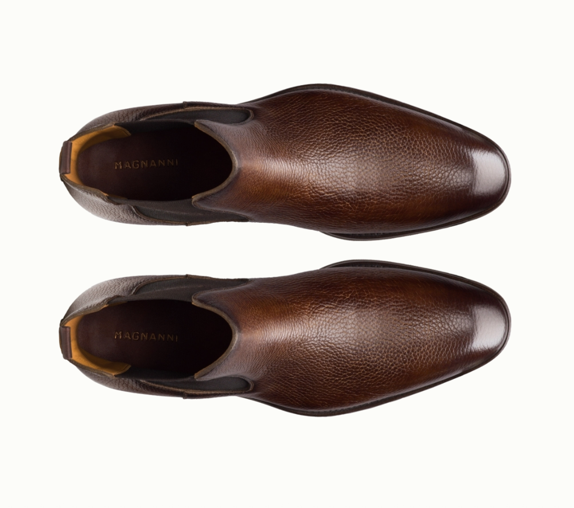 Top view of a pair of brown leather slip-on dress shoes with a textured finish, labeled MAGNANNI on the insole, displayed on a plain white background.