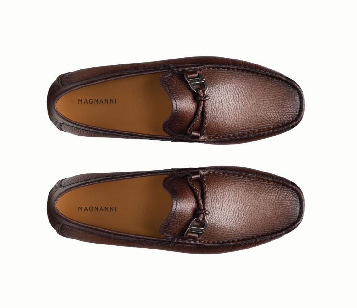 A pair of brown leather Magnanni loafers with a textured finish and metal bit detail, viewed from above against a white background.