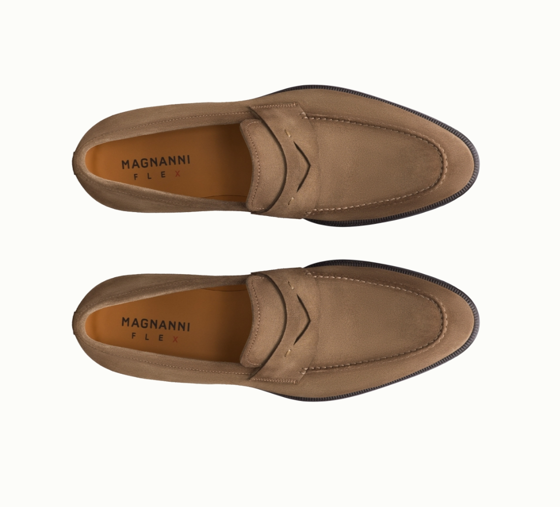 Top-down view of a pair of tan slip-on Magnanni Flex loafers with visible stitching and black outsoles, arranged side by side on a white background.