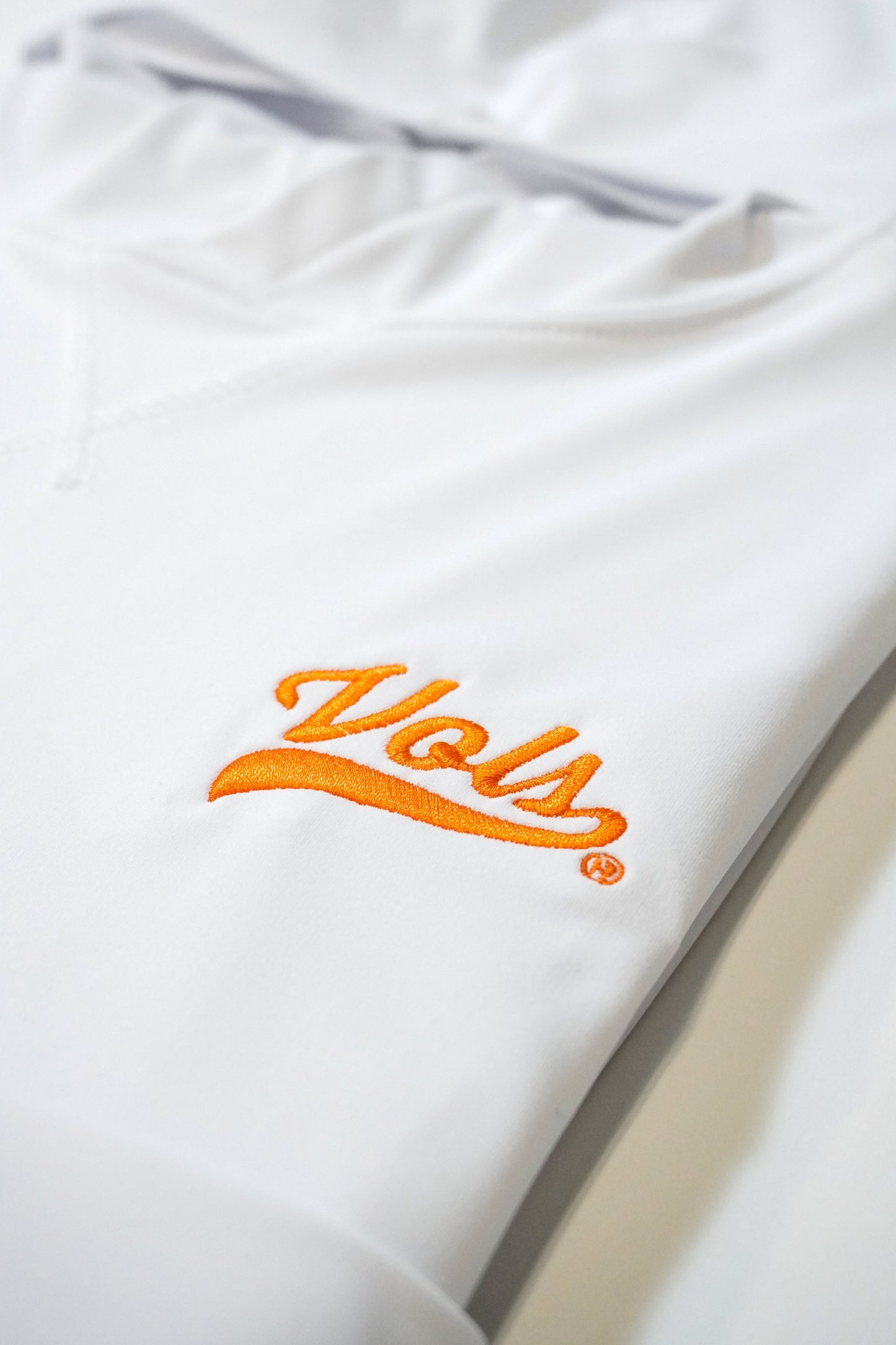 Close-up of a white hoodie with the word Vols embroidered in orange cursive lettering on the chest.