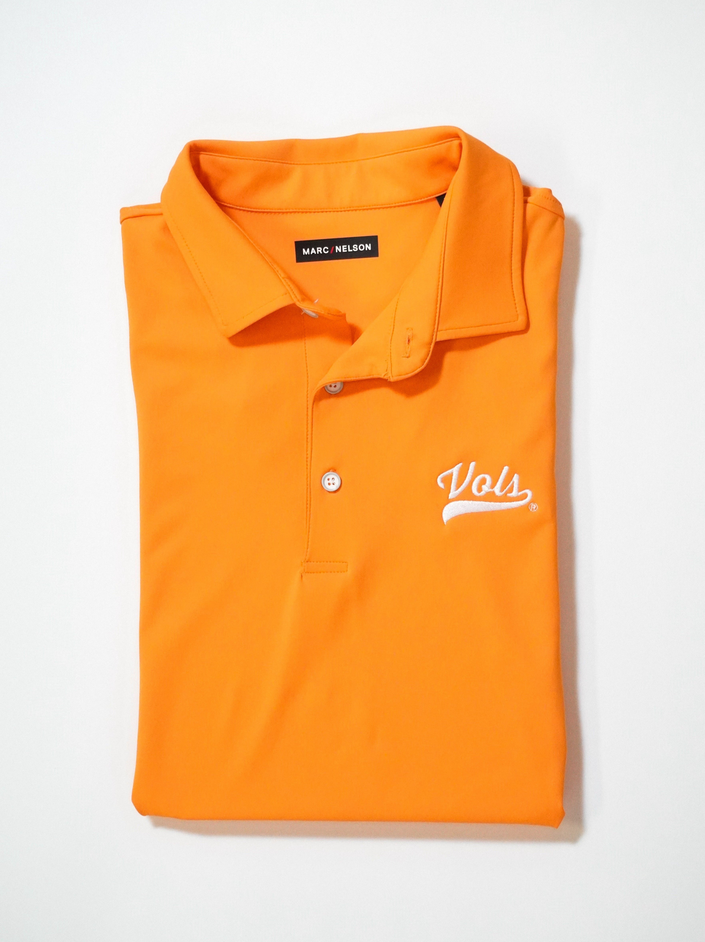 A folded orange polo shirt with Vols embroidered in white on the chest and a MARC NELSON label visible inside the collar, displayed on a white background.