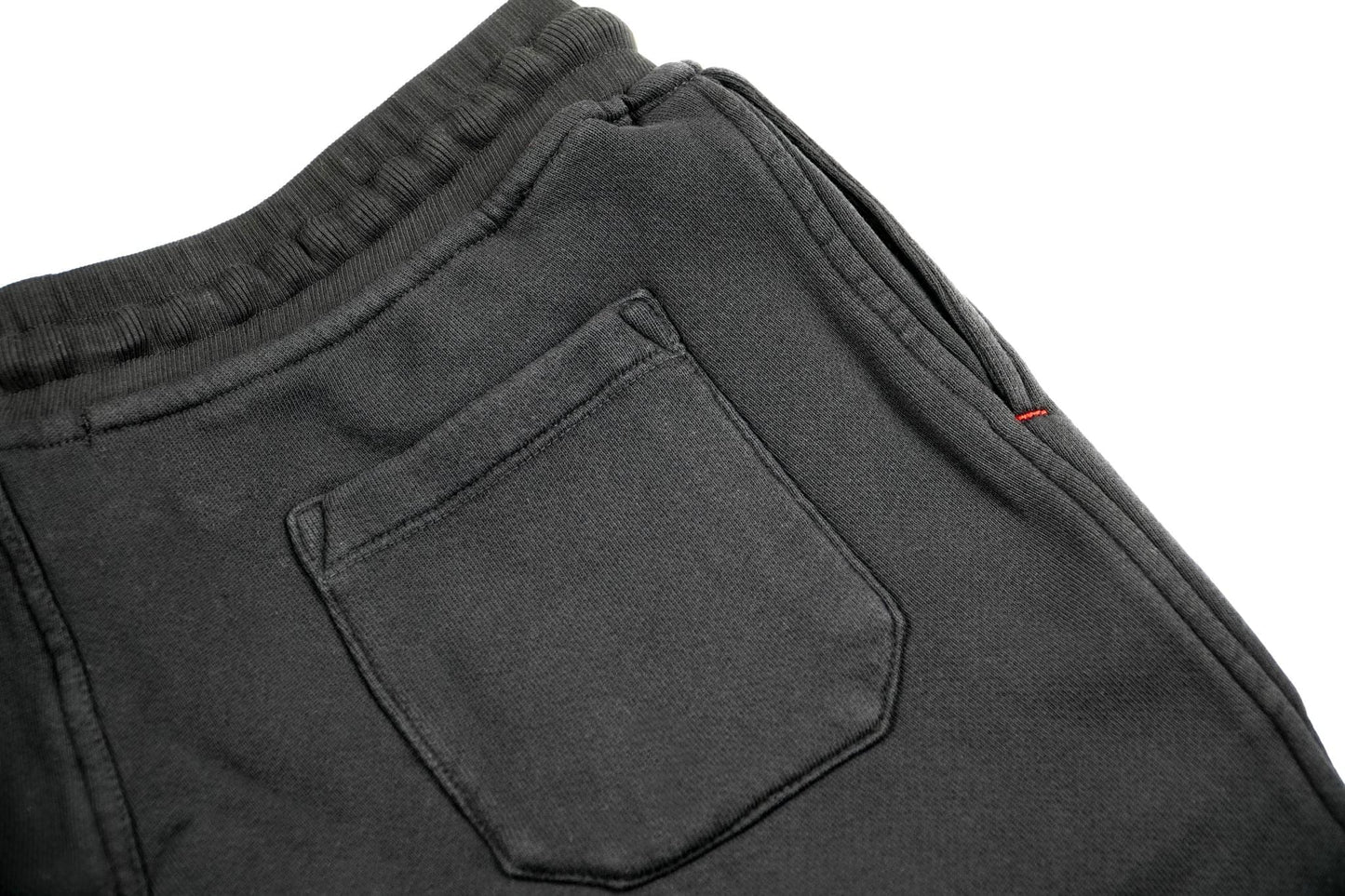Close up photo of black lounge shorts on a white background displaying the back pocket. 