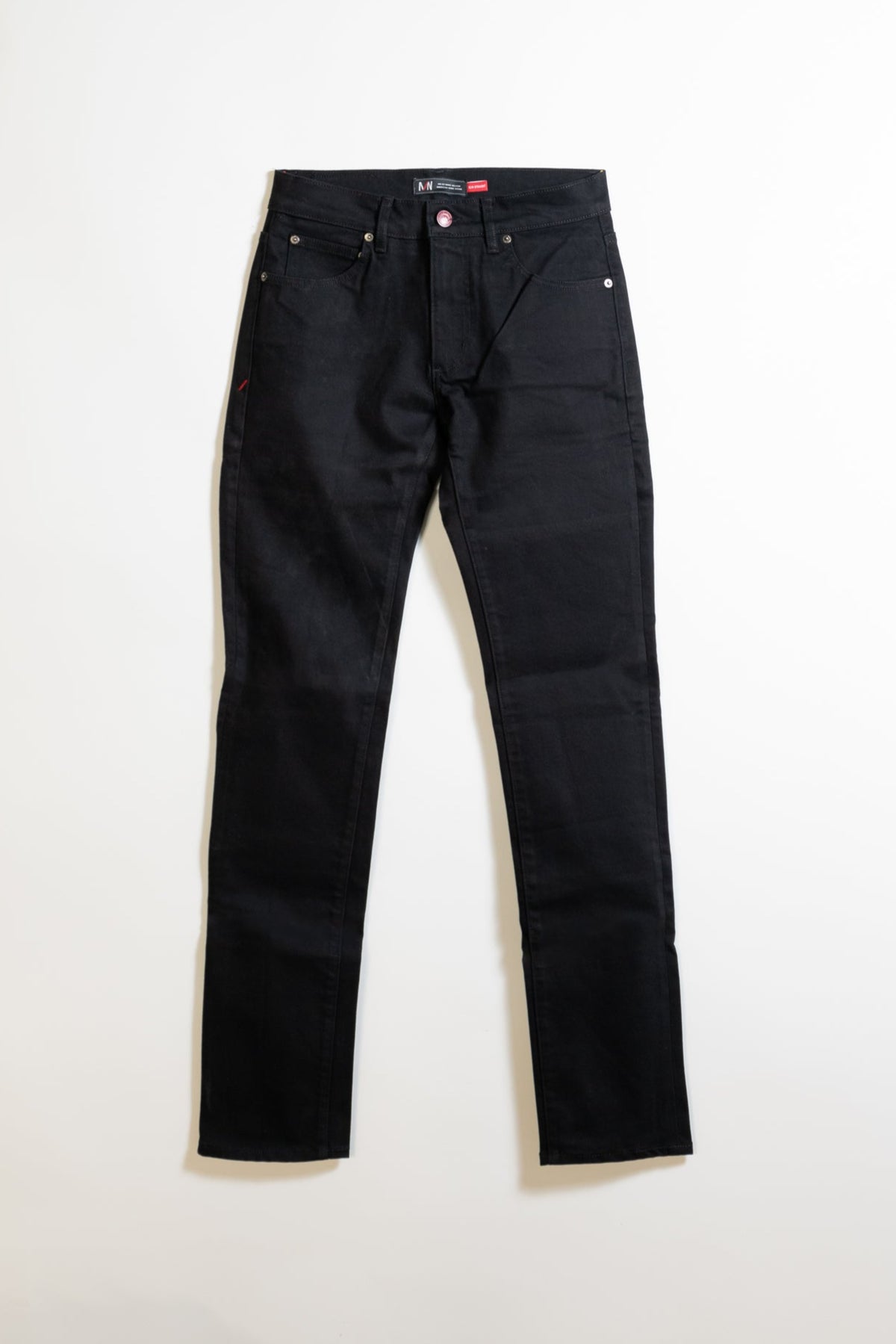 A pair of black denim jeans laid flat on a white background, showing the front side with five pockets and silver rivets.