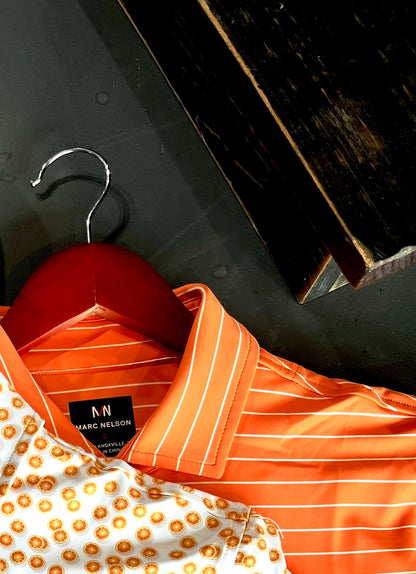 Close up lifestyle photo of orange polos on a clothing hanger.
