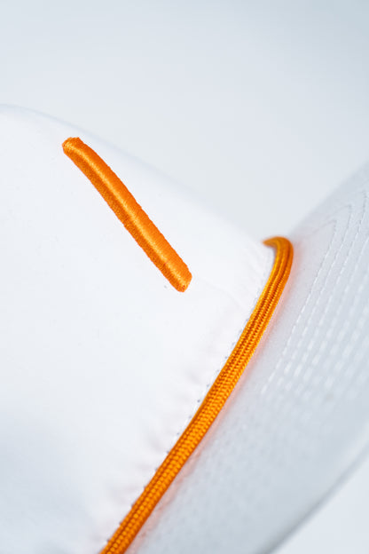 Close-up of a white cap featuring an orange embroidered line and orange piping along a seam, with part of the visor visible on the right side.