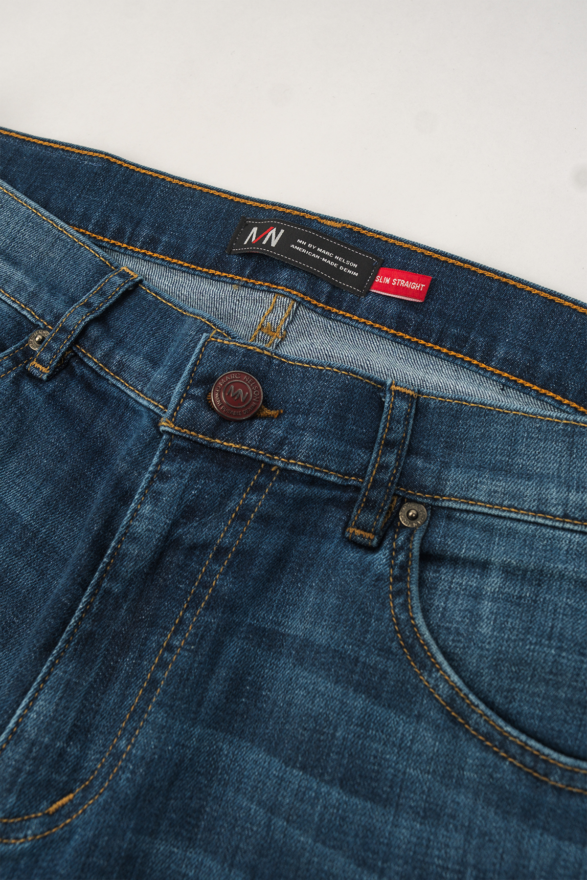 Close up photo of the front side of our medium wash denim of the button. 