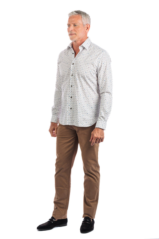A man wearing a patterned white button up and slim straight five pocket pants in 'Buck'.