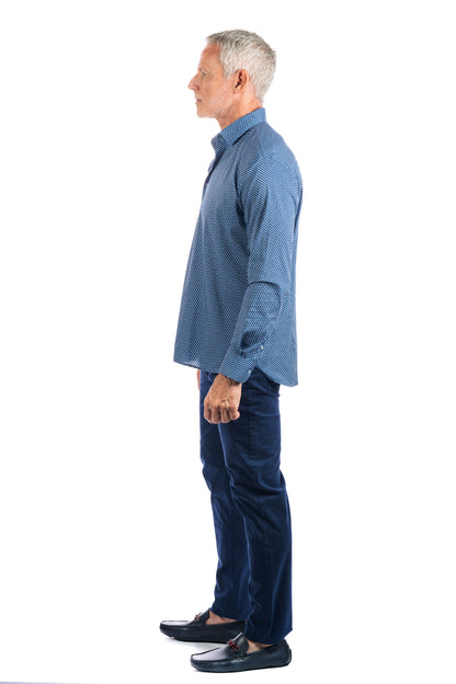 Side view of a man wearing a patterned navy button up and slim straight five pocket navy pants.
