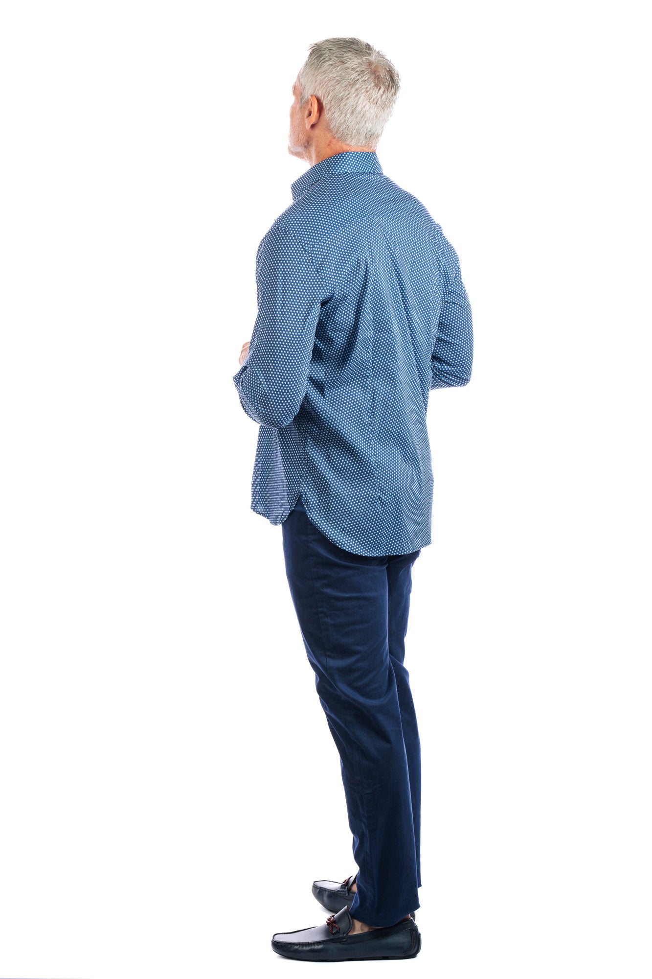3/4 back view of a man wearing a patterned navy button up and slim straight five pocket navy pants.