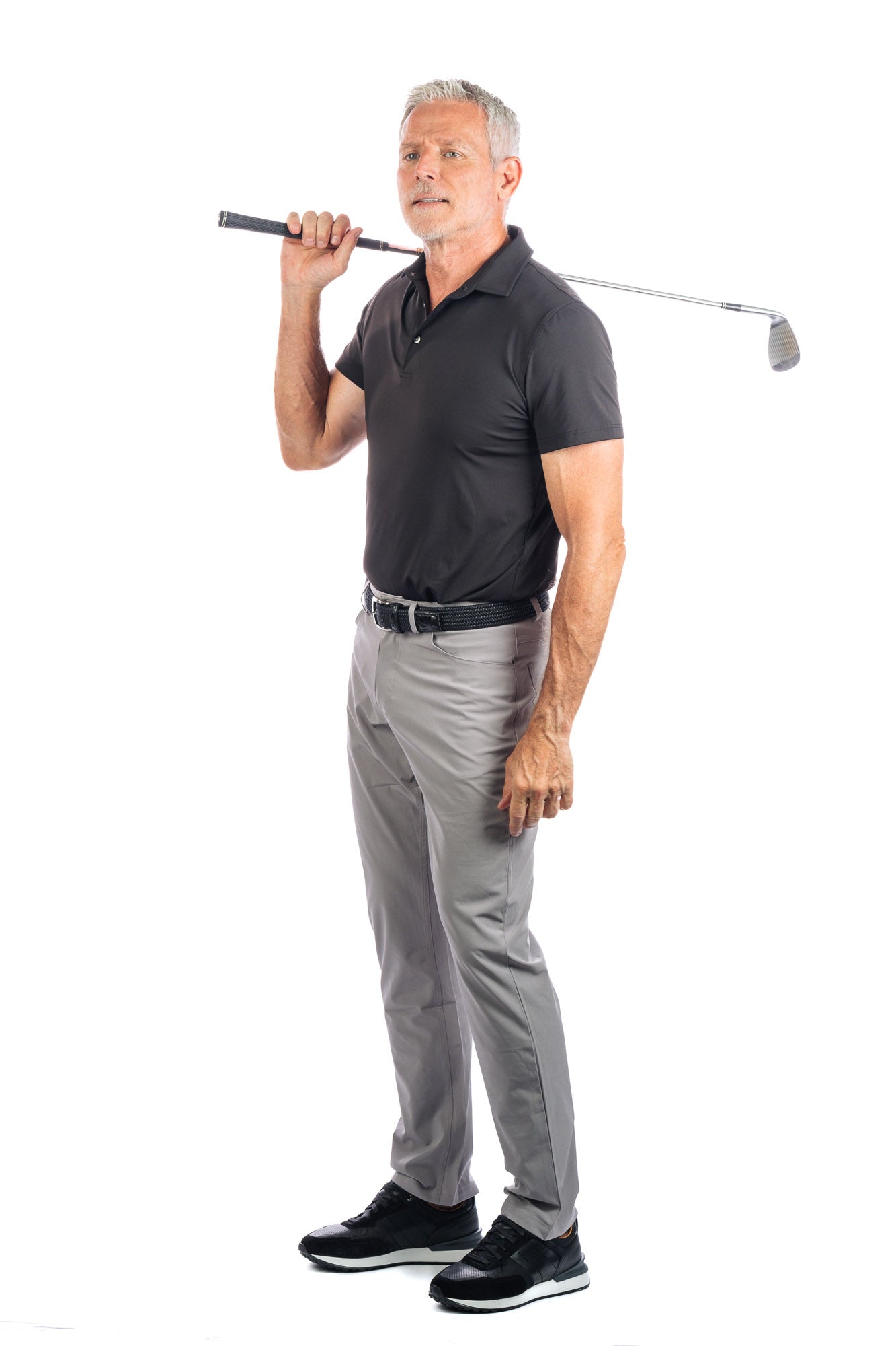 Side profile Photo of model wearing a black golf polo and concrete five pocket pants on a white background.