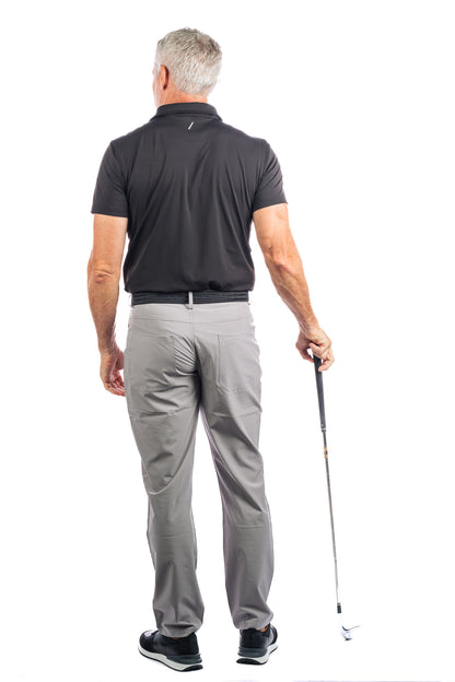 Back side Photo of model wearing a black golf polo and concrete five pocket pants on a white background.