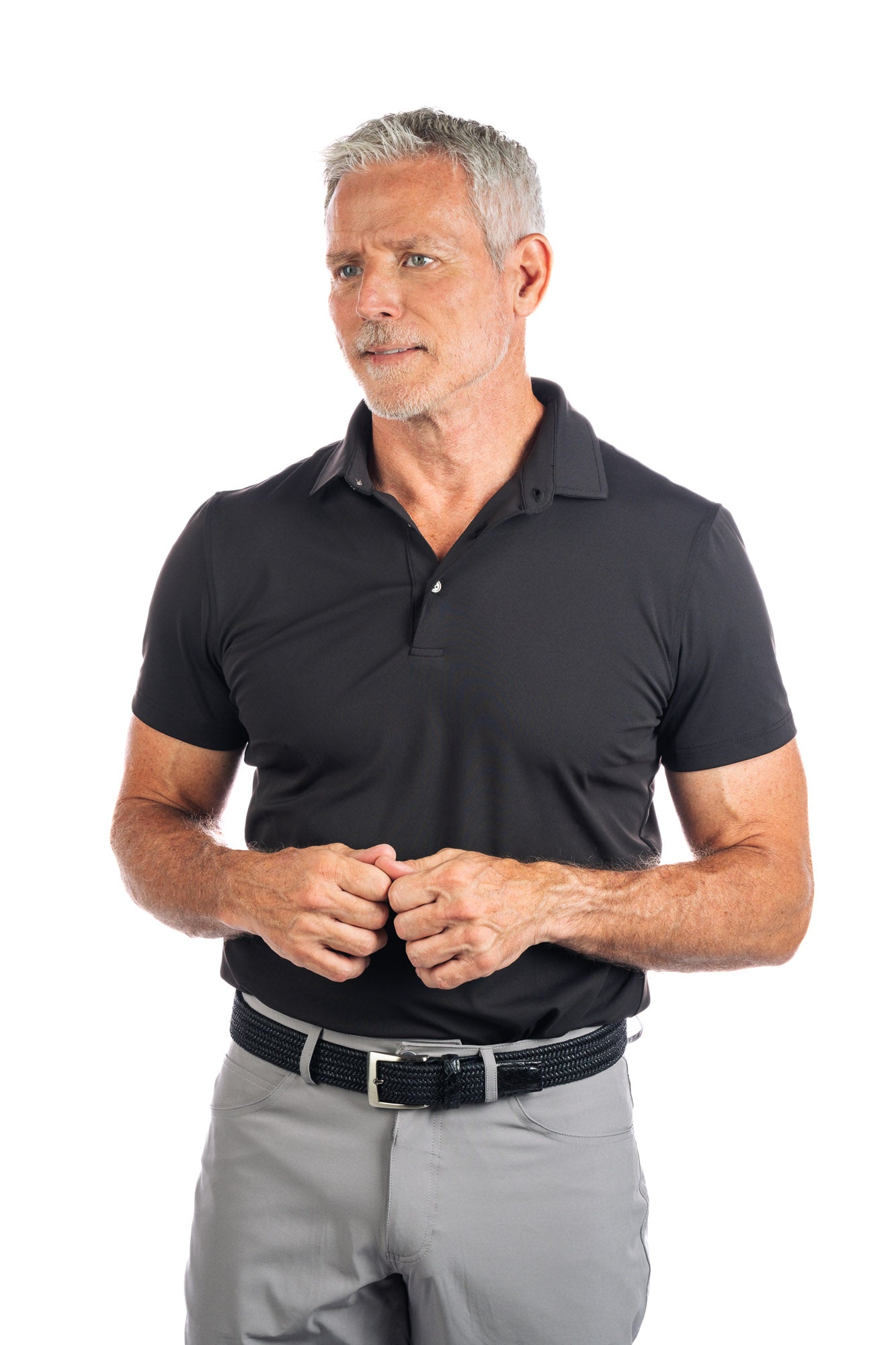 Photo of model wearing a black golf polo and concrete five pocket pants on a white background.