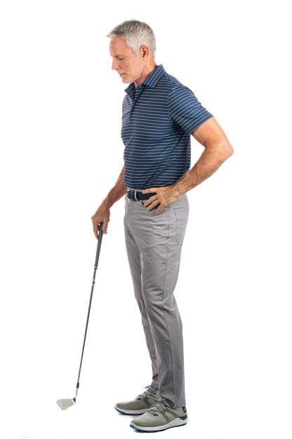 Side view of a model posing in a navy striped golf polo and grey pants, holding a golf club.