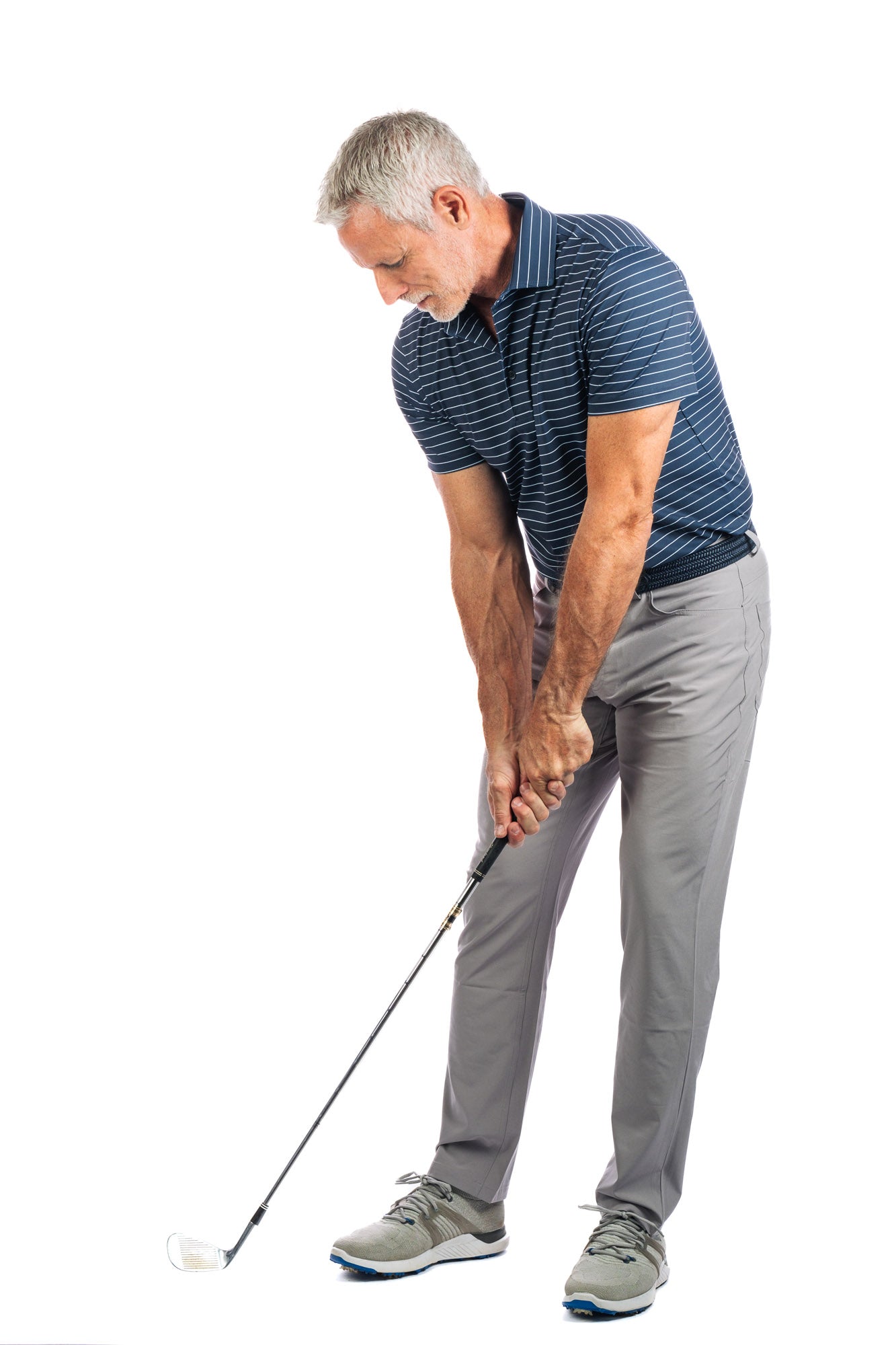 Front photo of model wearing navy polo with white stripes on a white background practicing his golf swing. 