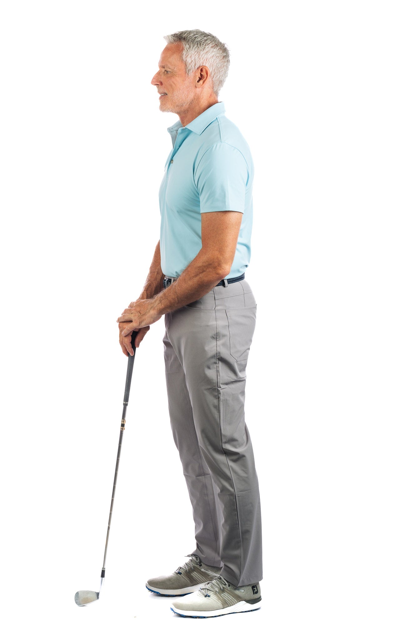 Side profile view of model wearing light blue golf polo and concrete golf pants looking away from the camera. 