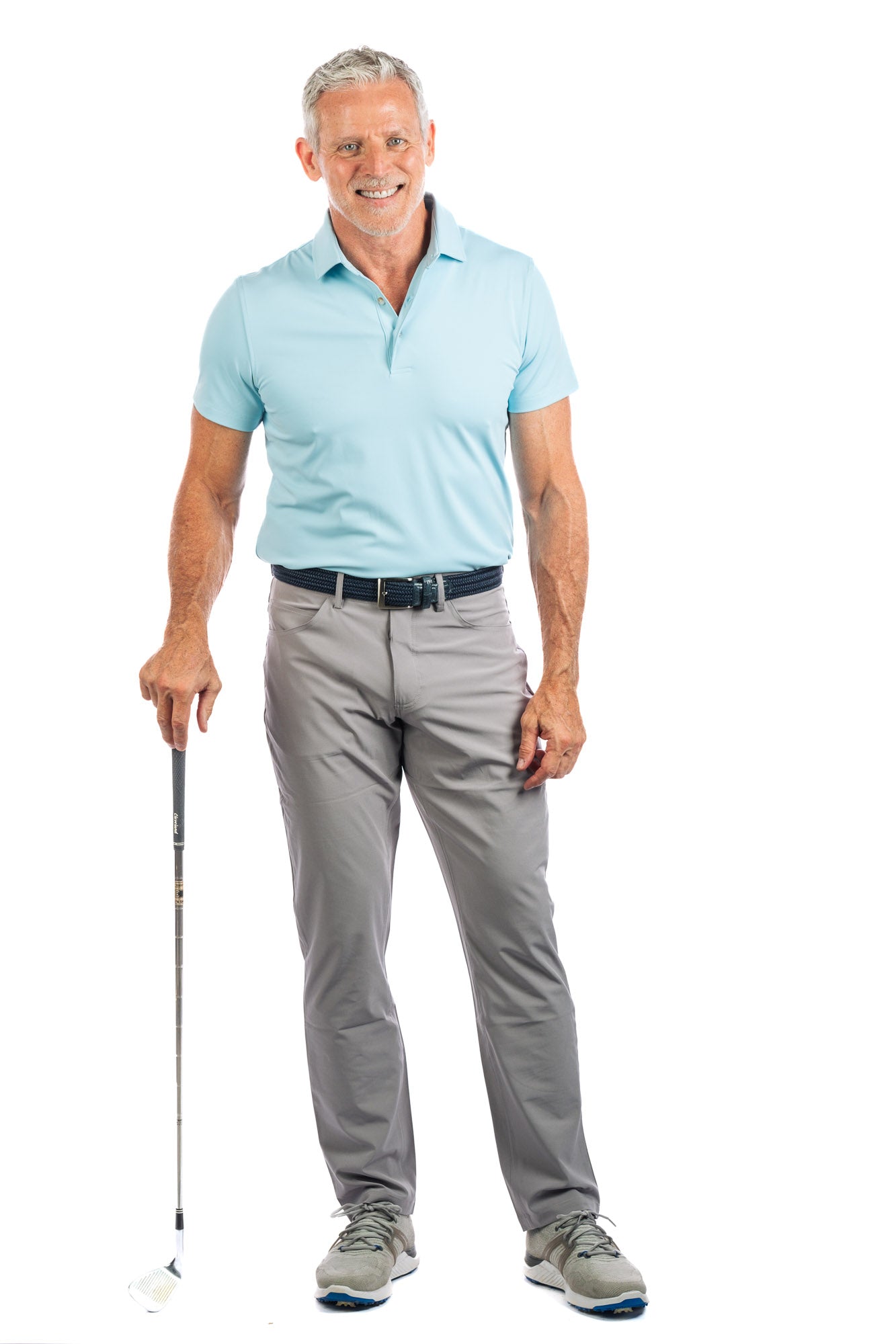 Front profile of model wearing light blue golf polo and concrete golf pants looking at the camera. 
