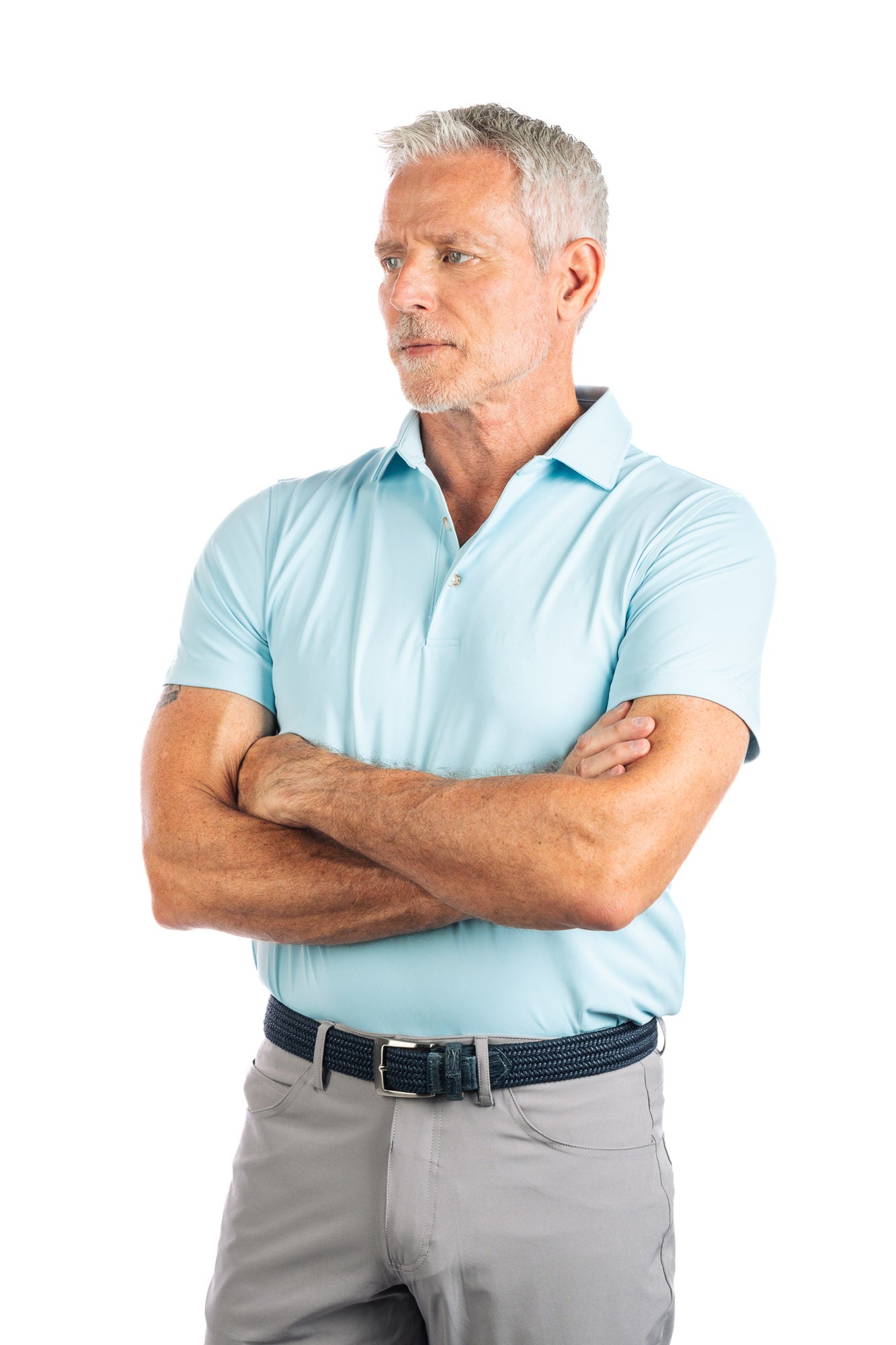 Waist up photo of light blue golf polo on white background on a model with his arms crossed. 