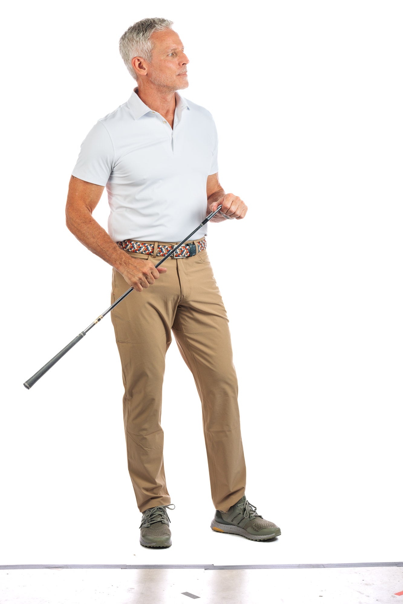 Photo of a model wearing our White Golf Polo on a White Background relaxed and looking to the right. 