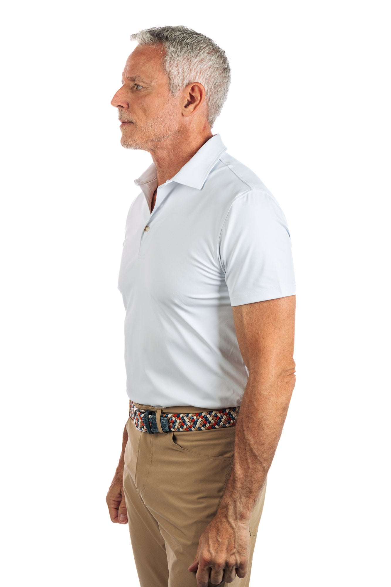 Photo of a model wearing our White Golf Polo on a White Background with his hands on his side and he is looking to the left. 