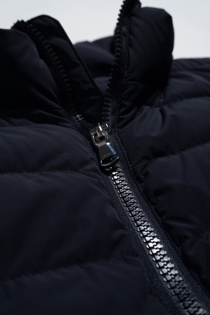 Close-up of a black quilted jacket featuring a shiny silver zipper partially unzipped, with visible stitching and puffy fabric texture.