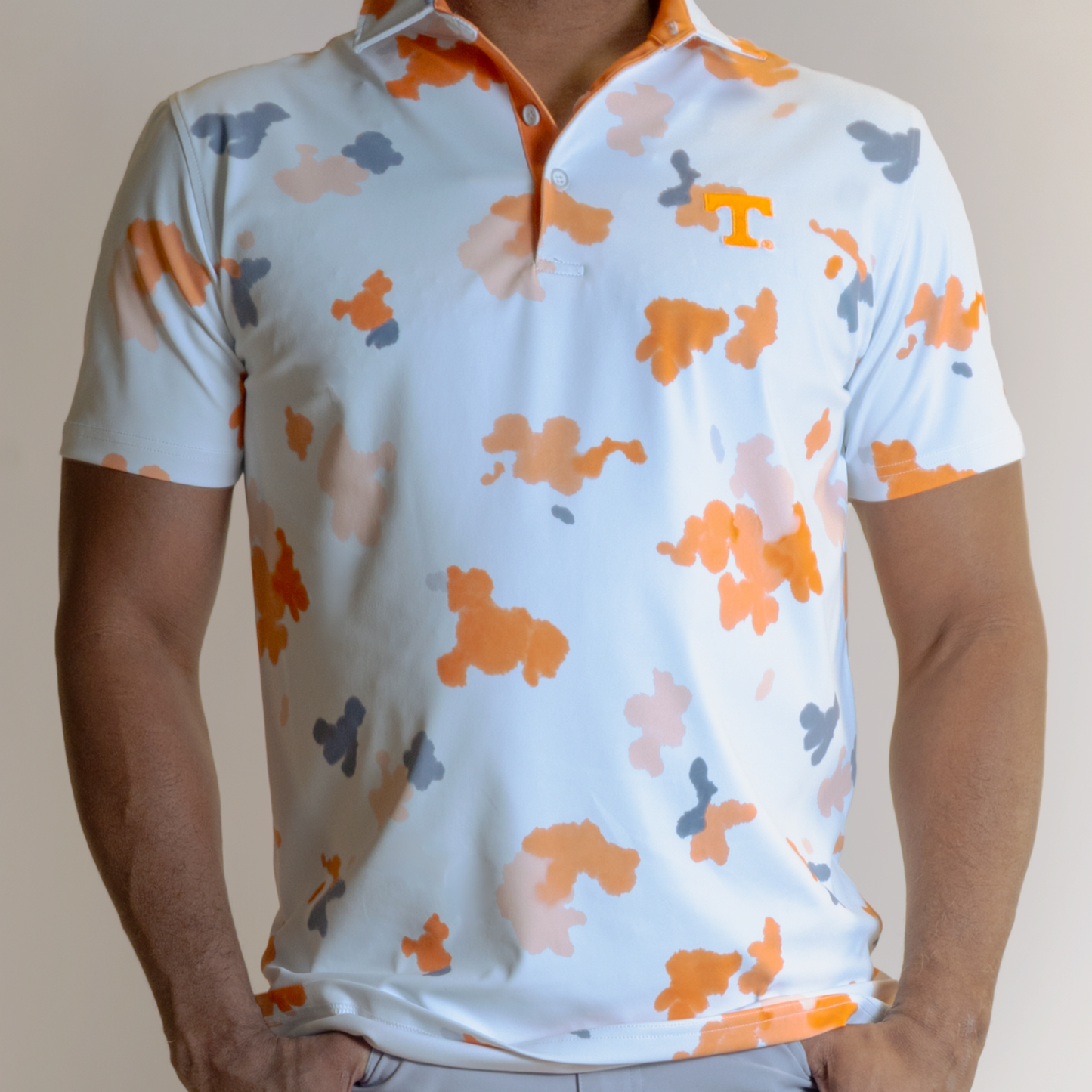 White polo shirt with colorful abstract pattern worn by a person on a neutral background