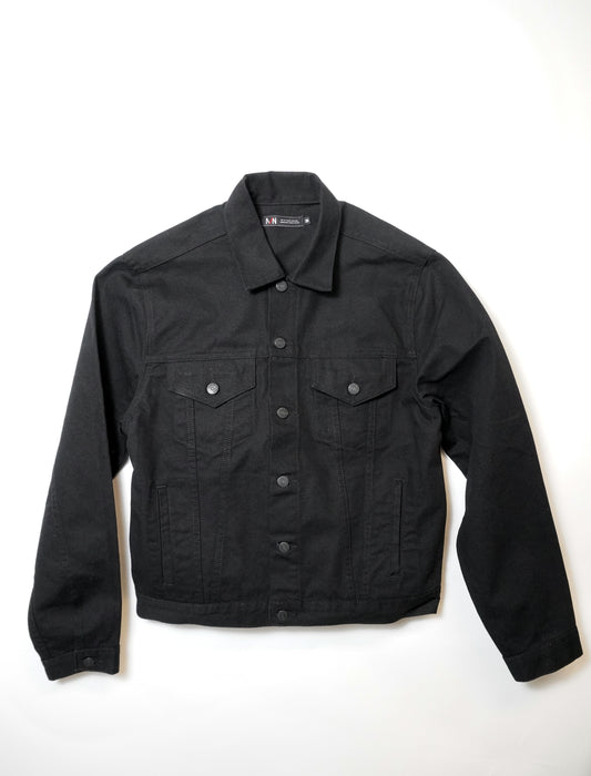 A black denim jacket with long sleeves, buttoned front, two chest pockets with flaps and buttons, and side pockets, laid flat on a white background.