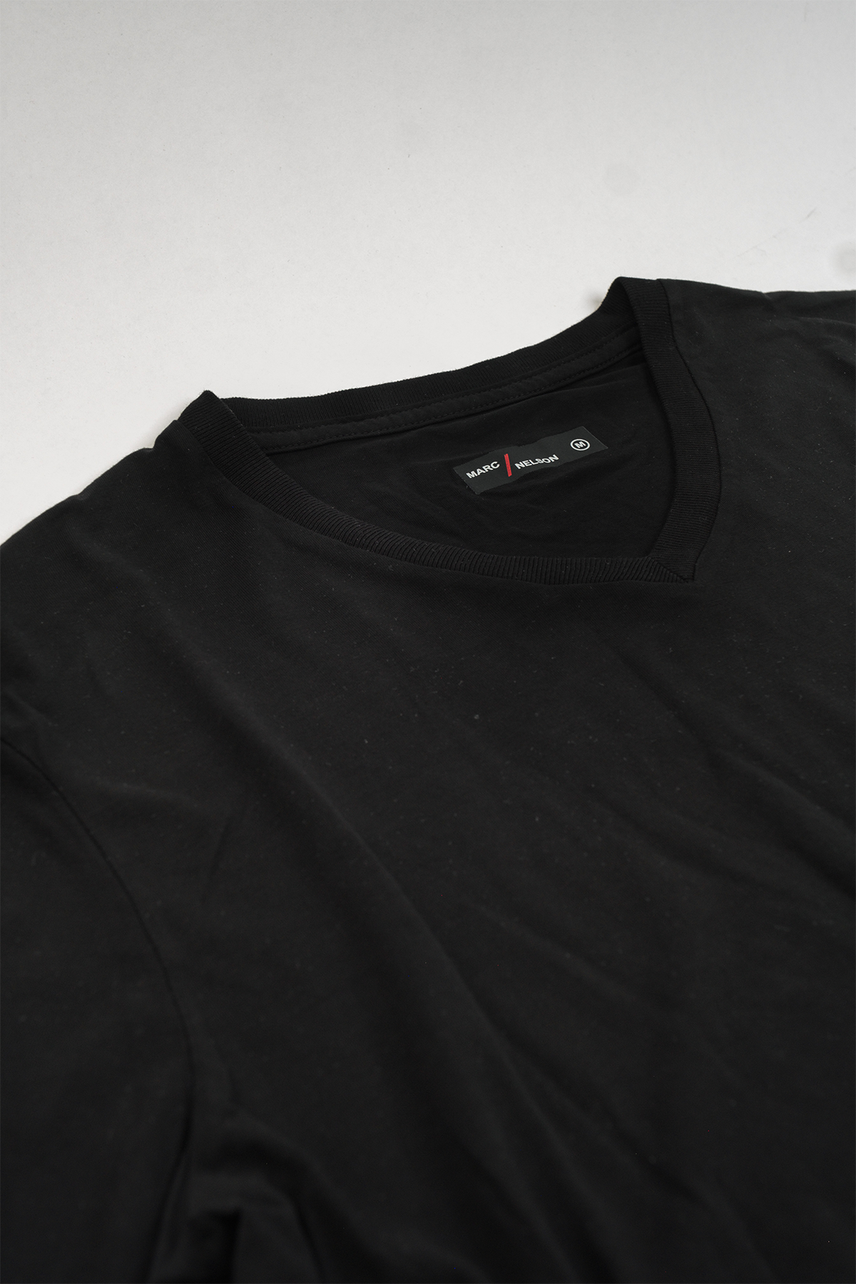 Close up of black v-neck t-shirt laid flat on a white background.