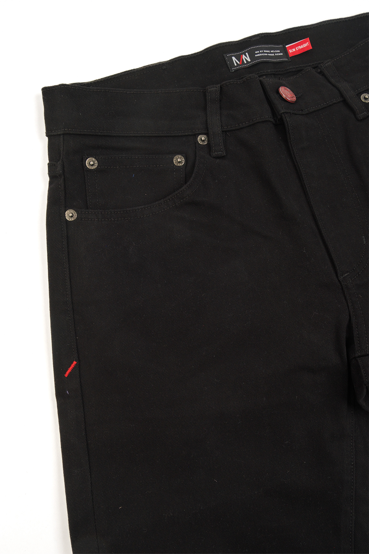 Close up photo of the frontside of black denim displaying the button and pockets.
