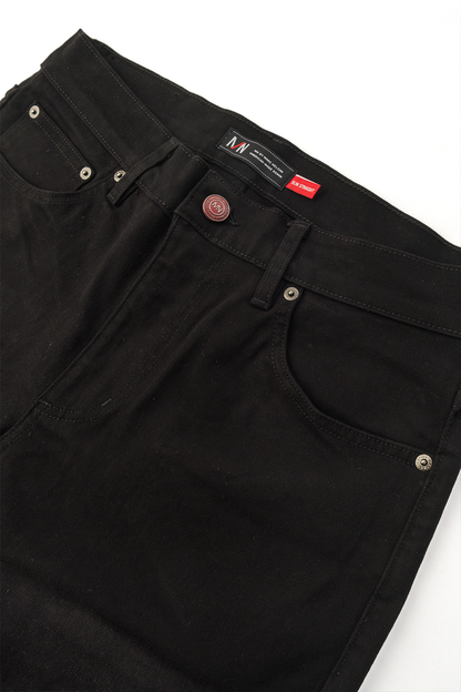 Close up photo of the frontside of black denim displaying the button and pockets. 