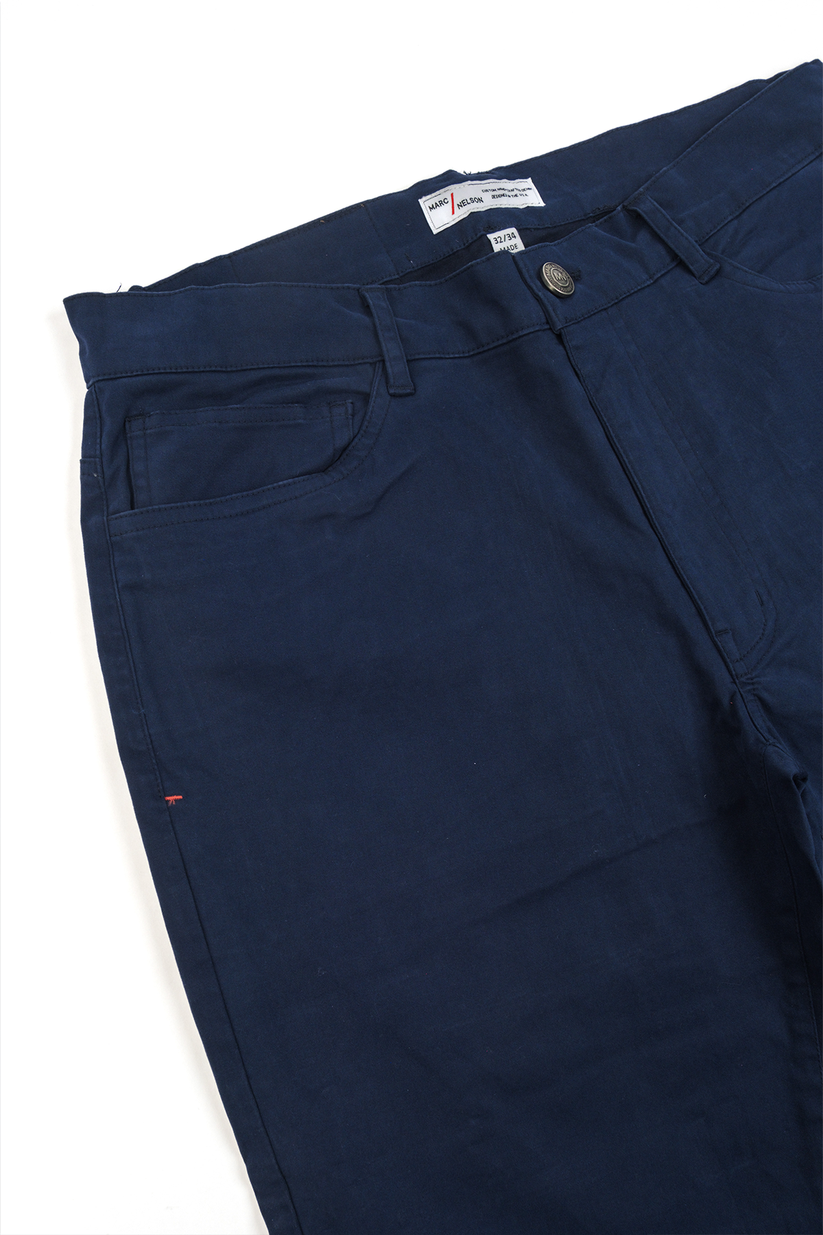 Close up photo of the frontside of the George Navy Pants focusing on the details of the button and the waist tag.