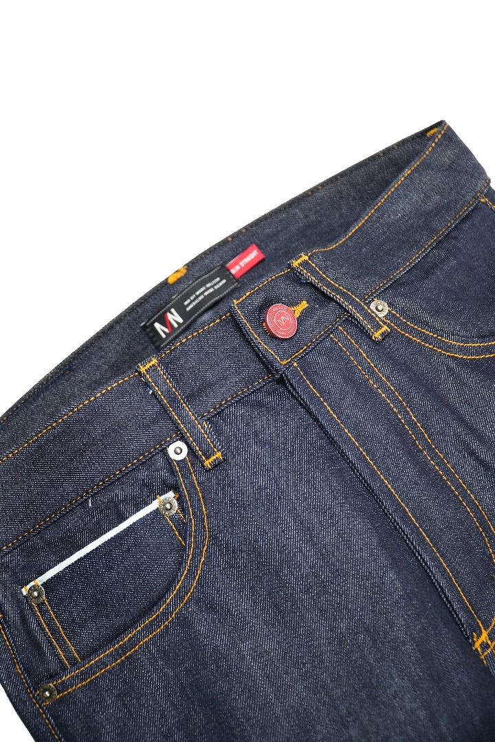 Close up photo of cone mills selvedge denim on a white background displaying the front button and pockets. 