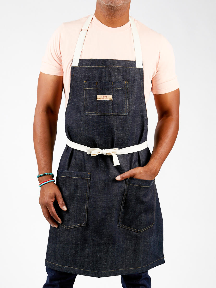 Photo of a model wearing the Common Apron in Indigo with his hand in his pocket. 