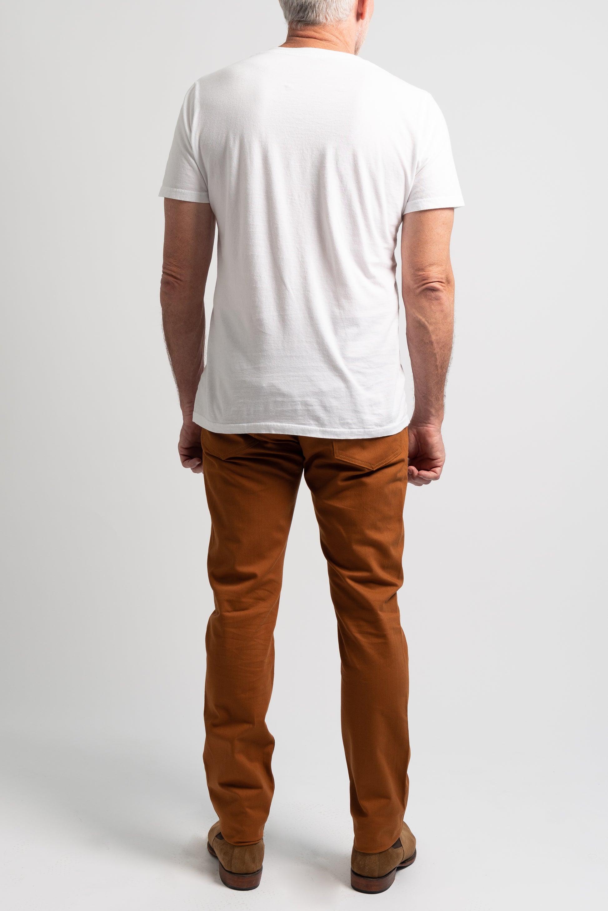 Full length photo of whiskey washed denim on a model wearing a white tee shirt on a white background facing backwards